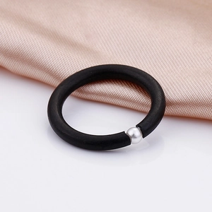 Minimalist matte black silicone ring with a single silver pearl on champagne satin