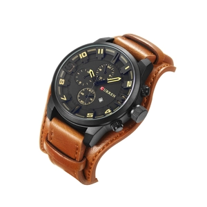 Detail of men's watch with black dial, yellow markers, and wide brown leather cuff strap