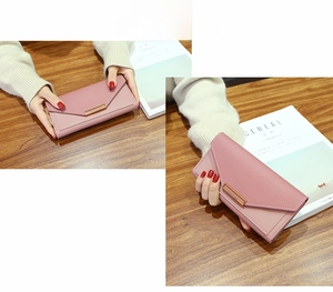 Detail of pink long envelope wallet with lychee leather texture and gold metal buckle