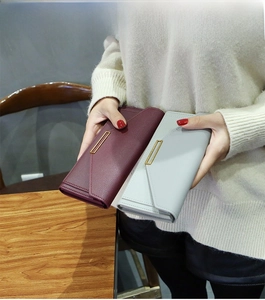 Detail of long leather wallets in burgundy and grey with elegant gold metal trim