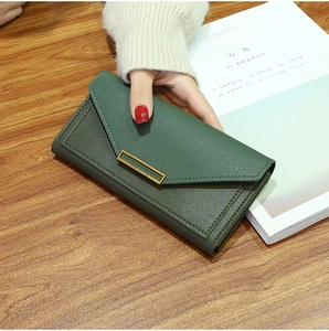 Detail of dark green textured leather long wallet with elegant gold metal buckle clasp