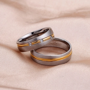 Two-tone matte stainless steel couple rings with three inlaid crystals on satin background