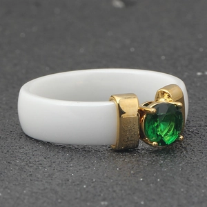 Macro view of 6mm white ceramic ring featuring a green gemstone in a gold-plated setting