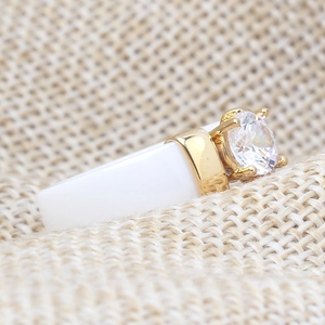 Macro detail of white ceramic ring with gold setting and large round cubic zirconia stone