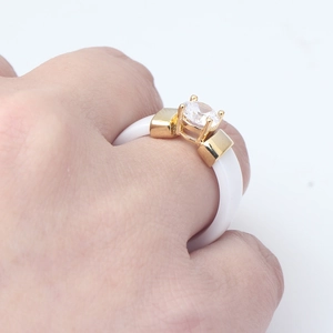 Detail of 6mm white ceramic ring featuring a round solitaire zircon and gold metal accents
