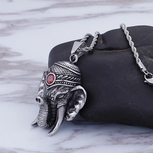 Silver elephant head pendant necklace with red gemstone and rope chain on black stone