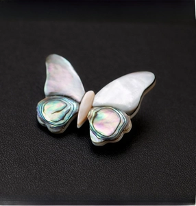 Macro shot of butterfly brooch with iridescent abalone shell wings on black leather