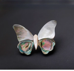 Detailed view of butterfly brooch with iridescent abalone shell wings on black leather