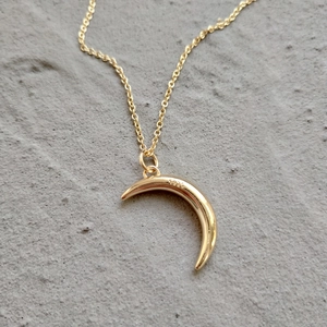 Close-up of S925 hallmark on a gold crescent moon pendant necklace over grey stone