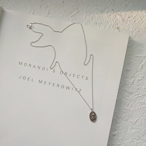 Detail of S925 sterling silver angel relief pendant on a ball chain over an art book