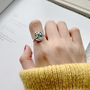 Close-up of vintage silver 925 portrait relief ring worn by model with yellow sweater