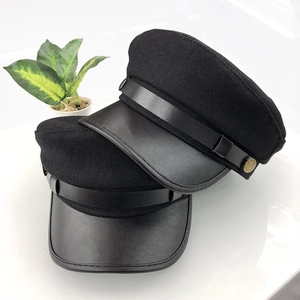 Detail of black wool police hat with leather brim and gold metal button accents