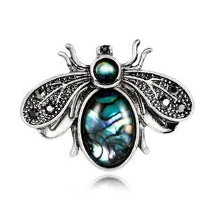 Detailed view of fly brooch with abalone shell body and black gemstone wings on silver metal