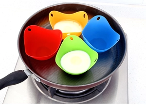 Detailed view of four colorful silicone egg poachers placed in a pan for boiling