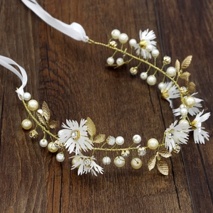Detailed close-up of handmade bridal headband with white petals and pearls on wood