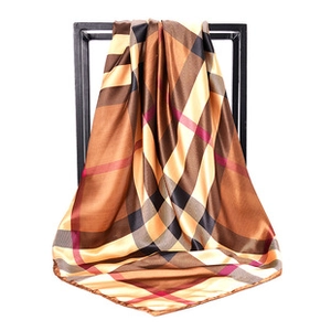 Detail of classic plaid pattern scarf in brown and beige draped over a black frame