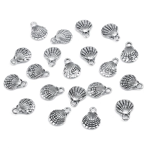 Macro view of silver shell-shaped alloy pendants for DIY jewelry on white background