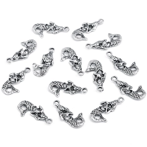 Flat lay macro of silver mermaid tail alloy pendants for DIY jewelry making