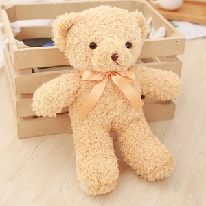 Plush teddy bear toy in warm beige with a silk ribbon bow on a wooden background