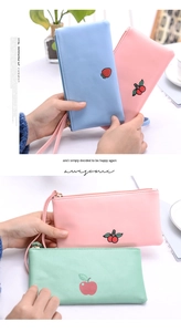 Detail view of macaron-colored coin purses with fruit embroidery and wrist straps