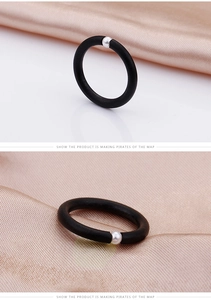 Detail of matte black minimalist ring featuring a single white pearl on satin fabric