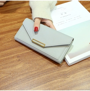 Macro detail of a light blue long leather wallet with a gold buckle on a wooden desk