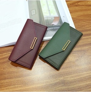 Detail of burgundy and dark green envelope wallets with litchi texture on a wooden desk