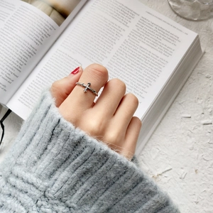 Close-up of retro S925 sterling silver twist cross open ring on hand with book background