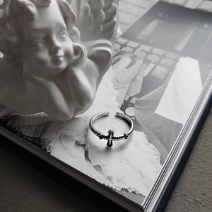 Macro detail of vintage S925 silver twist cross ring with antique finish on a white statue