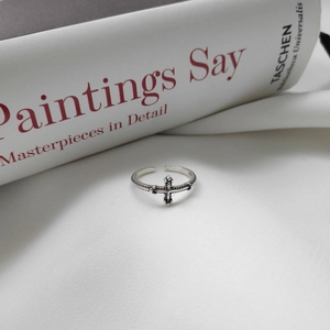 Detail of retro S925 sterling silver cross ring with oxidized finish on art book