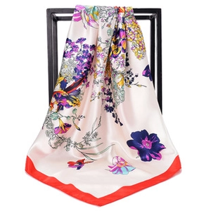 Detail of floral printed satin silk scarf with colorful blossoms and red border