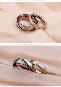 Detail of brushed titanium steel couple rings with black and gold textures and zircon