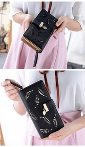 Detail of black long leather wallet with elegant gold hollow leaf patterns and zipper closure