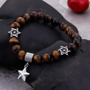 Tiger eye beaded bracelet with silver star charms on a natural dark stone background