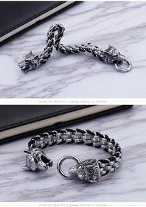 Detail of wolf head design on men's stainless steel bracelet with woven leather