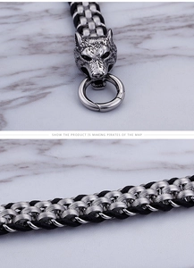 Detail of silver wolf head buckle and black leather braided chain on marble texture