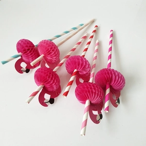 Detail of striped paper straws with pink honeycomb flamingo decorations on white background