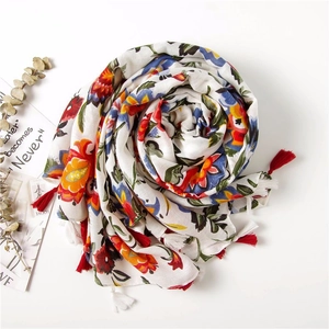 Close-up of lightweight cotton scarf featuring colorful floral print and red tassels