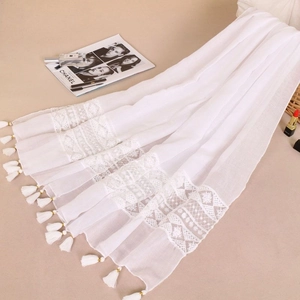 Detail of white lace patchwork scarf with tassel fringe edges and light texture