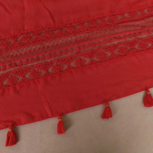 Detail of red scarf featuring hollow lace embroidery patterns and matching tassels