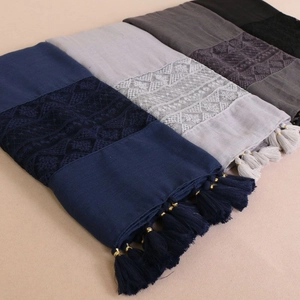 Detail view of lace trim and fringe tassels on tiered solid color scarves