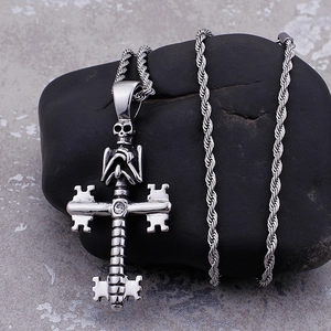 Stainless steel skull cross necklace with clear gemstone on dark stone background