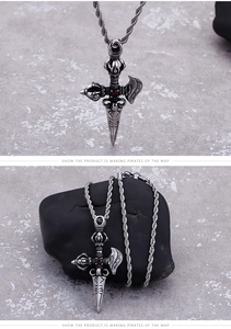 Detailed view of silver stainless steel vajra pendant with red stone on dark stone surface