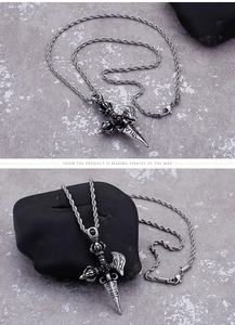 Detail of vintage titanium steel vajra pendant with red zircon on a rugged rope chain