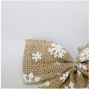 Macro detail of red linen Christmas bow with white snowflake pattern and silver wire tie