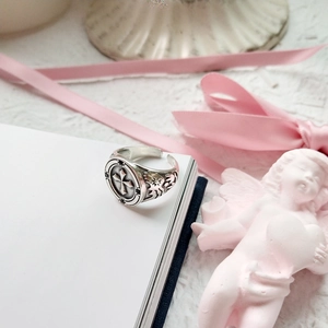 Detail of vintage sterling silver cross ring on a notebook with romantic decor