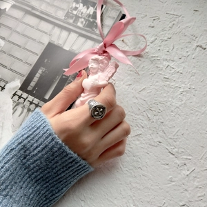 Detail shot of vintage silver cross ring worn on finger with artistic background