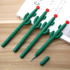 Detailed view of four green cactus pens with red flowers on a wooden desk with a magazine