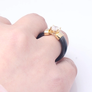Detailed view of black ceramic ring with gold inlay and a sparkling zircon stone
