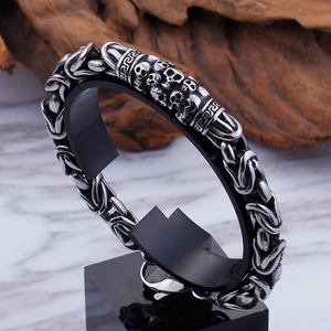 Gothic titanium steel skull bracelet with Greek fret pattern on black stand